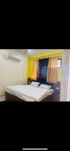 1 dormitorio con cama blanca y ventana en SN hotel inn and restaurant, en Sikandarābād