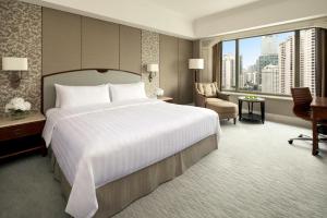 a bedroom with a large white bed and a chair at Shangri-La Jakarta in Jakarta