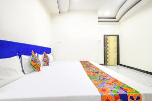 a bedroom with a white bed with colorful pillows at FabExpress High Star in Ujjain