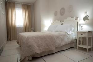 a white bedroom with a white bed and a window at Le case del Duca in Ioppolo Giancaxio