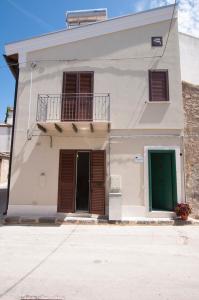 a white house with a green door and a balcony at Le case del Duca in Ioppolo Giancaxio