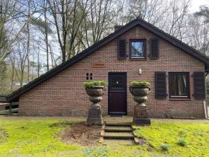una casa de ladrillo con una puerta y dos macetas de flores en 't Aarthuis en Emst