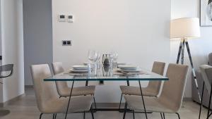 mesa de comedor con sillas y mesa de cristal en SUNSET WAVES luxury apartment, en Benidorm
