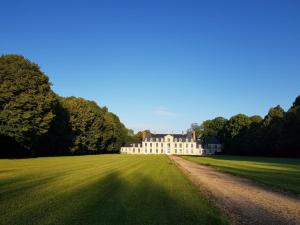 a large white house in a grassy field at Chateau de Tosny in Tosny