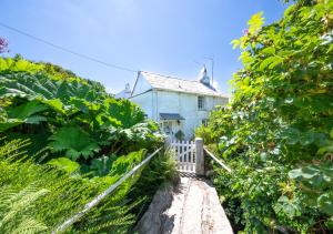 an old house with a white fence in a garden at Riverside in Saint Breward