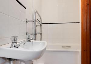 a white bathroom with a sink and a bath tub at Riverside in Saint Breward