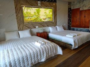 a bedroom with two beds and a painting on the wall at Sông Hotel PQ - by BAY LUXURY in Phu Quoc
