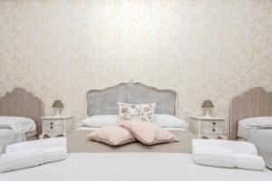 a white bedroom with two beds and two night stands at PALAZZO ALESSANDRINI GUEST HOUSE in Viterbo