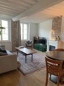 een woonkamer met een bank, een tafel en een open haard bij 123 Honfleur in Honfleur