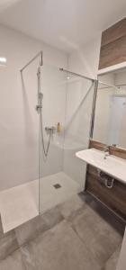 a bathroom with a glass shower and a sink at Apartament Czarna Góra MOON in Sienna