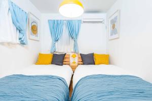 two beds in a small room with blue curtains at Modern House Tokyo east in Tokyo
