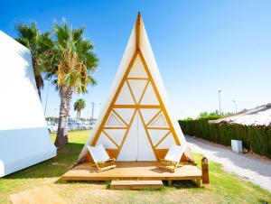 namiot tipi z dwoma krzesłami i palmami w obiekcie Kampaoh Costa Blanca w mieście Torre de la Horadada