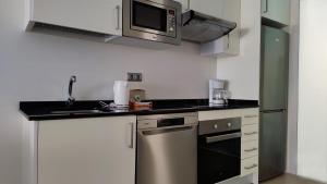 een keuken met een wastafel en een magnetron bij MIRADOR Poniente beach apartments in Benidorm
