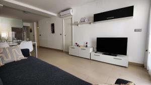 een woonkamer met een bank en een flatscreen-tv bij MIRADOR Poniente beach apartments in Benidorm