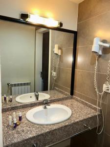 a bathroom with a sink and a large mirror at Iris Flower Hotel in Jezzîne