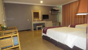 a hotel room with two beds and a desk at Heritage Hotel in Tawau