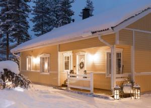una casa en la nieve con luces encendidas en Arctic Circle Home close to Santa`s Village, en Rovaniemi