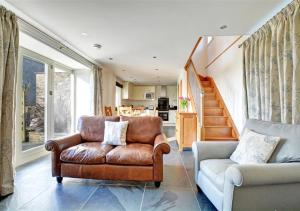 a living room with a leather chair and a couch at The Well House Trevisquite in Saint Tudy