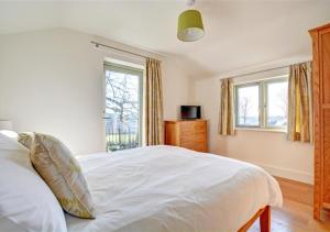 a bedroom with a white bed and two windows at The Well House Trevisquite in Saint Tudy