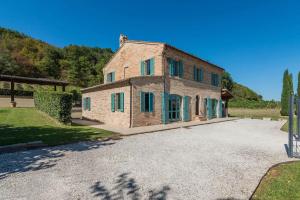 a large stone house with green windows on a driveway at Casale Vigneto in Mogliano