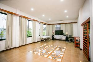 a living room with a table in a room with windows at บ้านเราอุทัยธานี โฮมสเตย์ in Uthai Thani