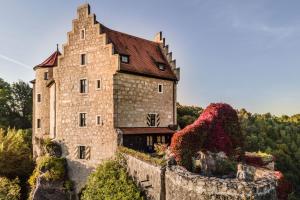 una vieja casa de piedra en una colina con flores en Burg Rabenstein en Kirchahorn