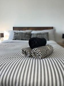 City View Apartment في ديربي: سرير عليه أغطية ومخدات سوداء وبيضاء