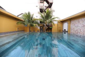 - une grande piscine avec des palmiers dans un bâtiment dans l'établissement Vĩnh Phong 2 Hotel Phú Quốc - by Bay Luxury, à Duong Dong