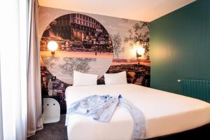ibis styles Paris Montmartre Batignolles في باريس: غرفة نوم مع سرير أبيض كبير مع لوحة على الحائط
