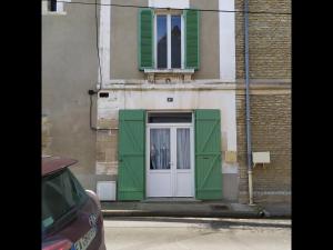 un edificio con persianas verdes y una puerta en La Parenthèse Côtière - Moins d’un km de la plage, en Courseulles-sur-Mer