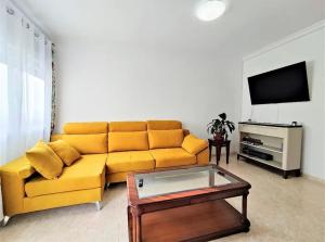 sala de estar con sofá amarillo y TV en Continental Gandia - Private rooms TV, en Gandía