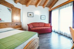 una camera con un letto e una sedia e una finestra di Hotel Bel Soggiorno a Malosco
