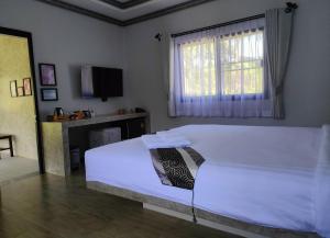 a bedroom with a white bed and a window at Century Hotspring Resort in Phra Chedi Sam Ong