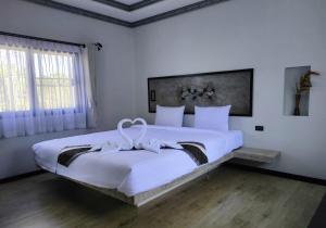 a bedroom with a large white bed with a bow on it at Century Hotspring Resort in Phra Chedi Sam Ong