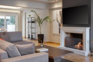ein Wohnzimmer mit einem Kamin und einem Flachbild-TV in der Unterkunft Athenian Grand Riviera Villa in Athen
