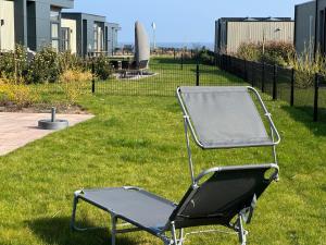 a folding chair sitting on the grass in a yard at Enkhuizer Strand Chalet Hafenplätzchen mit Zaun Haus Nr 244 in Enkhuizen