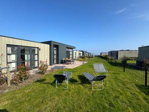 a yard with two lawn chairs and a house at Enkhuizer Strand Chalet Hafenplätzchen mit Zaun Haus Nr 244 in Enkhuizen