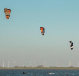 três pessoas estão a fazer kite-surf na água em Freie Sicht - Das Nordsee-Gesundheitshaus 2 em Dagebüll