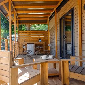 un portico di una cabina in legno con tavolo e sedie di Il Pampaleone Glamping and Resort ad Acireale