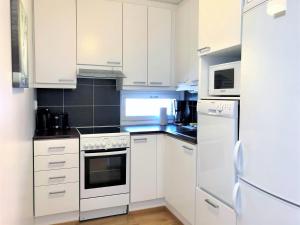 タンペレにあるKotimaailma Apartments - tilava yksiö - Pellavantori 2の白いキッチン(白いキャビネット、電化製品付)