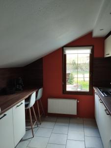 a kitchen with red walls and a window at La Mansarde in La Chapelle-aux-Bois