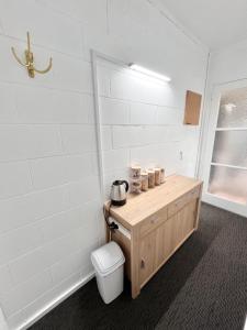 a bathroom with a toilet and a white wall at House of Somer in Matamata