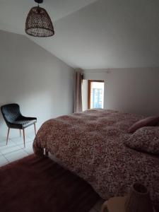 a bedroom with a bed and a chair and a window at La Mansarde in La Chapelle-aux-Bois