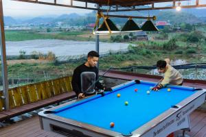 dos hombres jugando al billar en una terraza en Stella Mộc Châu Homestay, en Mộc Châu