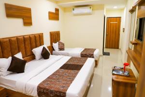 a hotel room with two beds and a television at Hotel The Grand in Ahmedabad