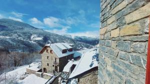 un edificio cubierto de nieve con montañas de fondo en Apartament Rural Burg, en Burg