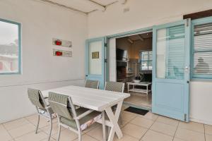 a dining room with a white table and chairs at Duintjie Beach Cottage in Paternoster