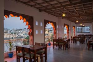 um restaurante com mesas e cadeiras e uma varanda em Hotel Dera Pichola em Udaipur