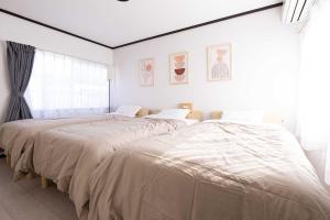 2 Betten in einem weißen Schlafzimmer mit einem großen Fenster in der Unterkunft Lino下伊福 in Okayama