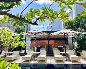 un patio junto a la piscina con mesas, sillas y sombrillas en Hotel Palm Royal Naha Kokusai Street, en Naha